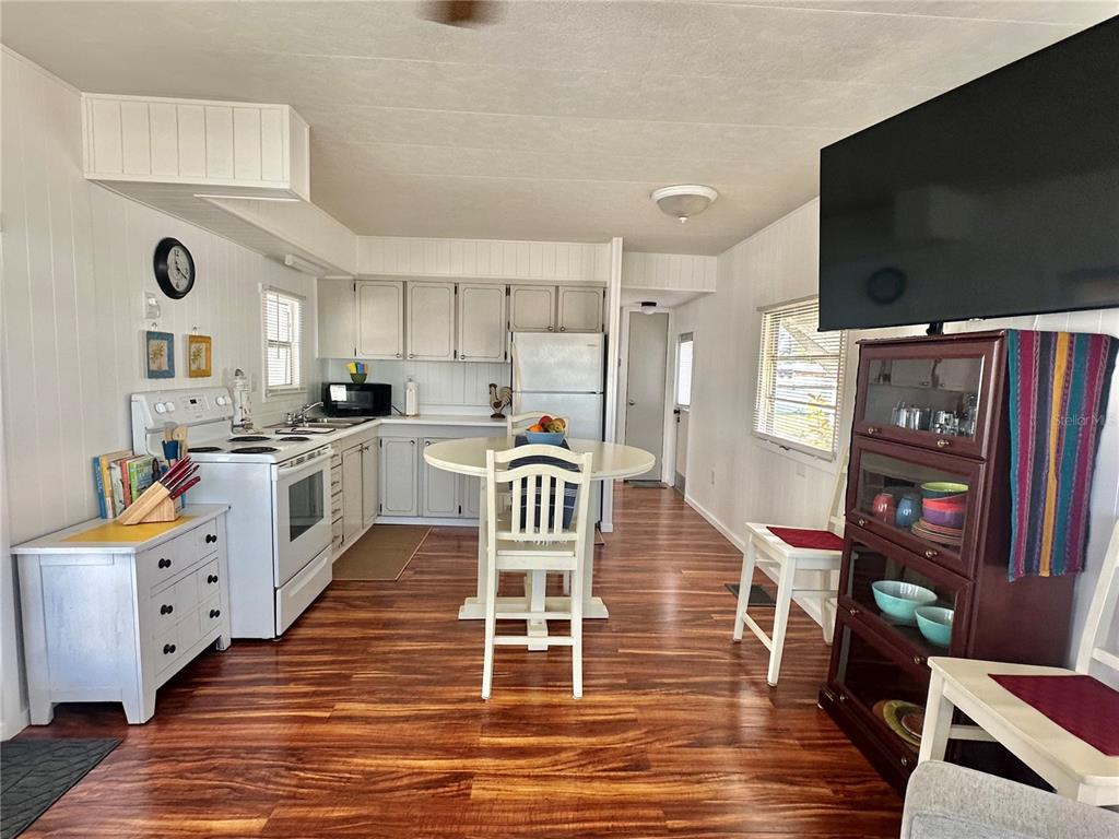 A kitchen and dining area with white cabinetry, a round table, and wood-look flooring — 1501 25TH AVENUE DRIVE W, BRADENTON, FL