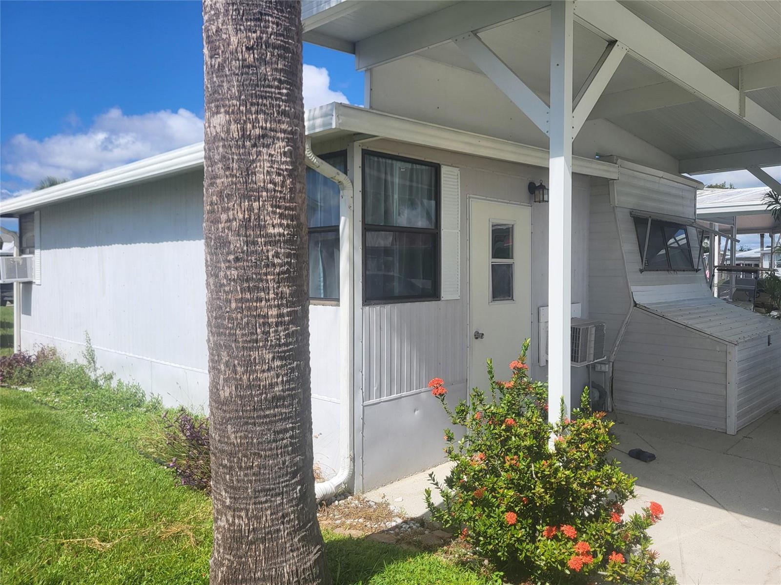 A mobile home exterior features a palm tree, a small porch, and a white door — 6502 SE 54th Lane, Okeechobee FL 34974, OKEECHOBEE, FL