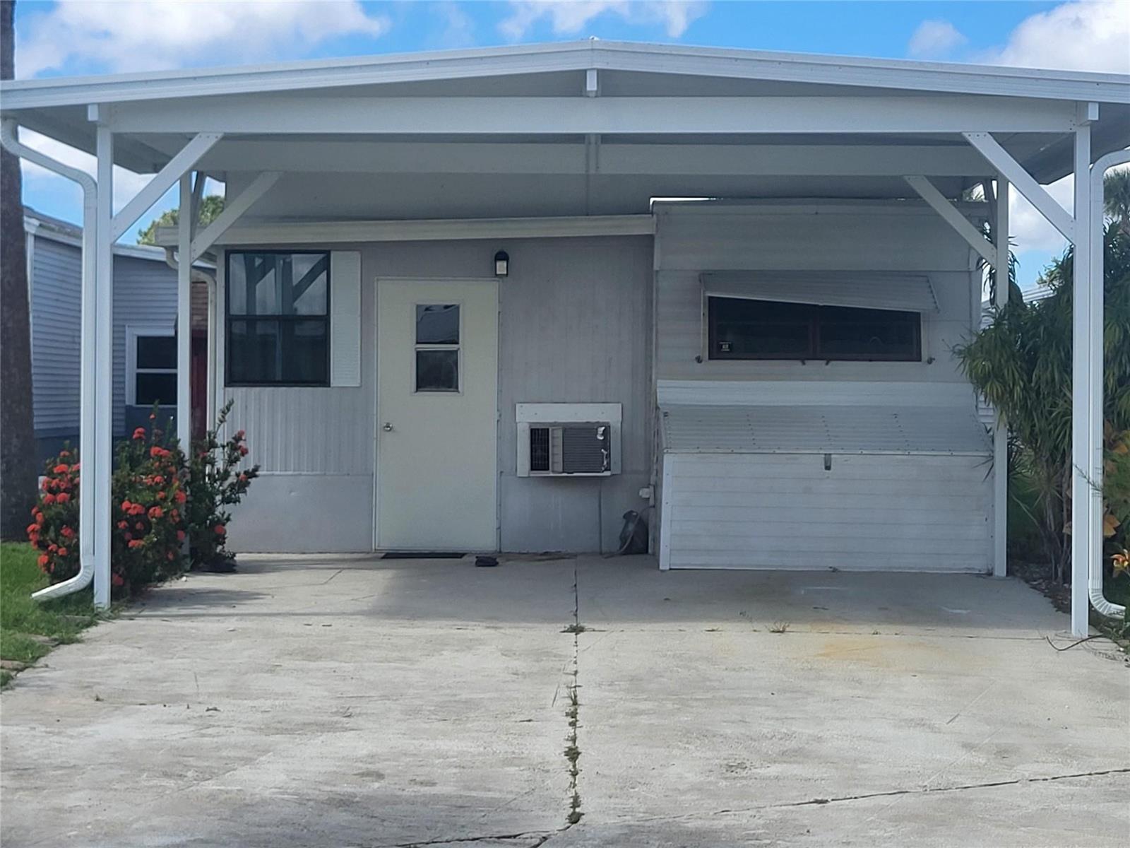 The exterior of a mobile home features a concrete driveway, a carport, and an air conditioner — 6502 SE 54th Lane, Okeechobee FL 34974, OKEECHOBEE, FL