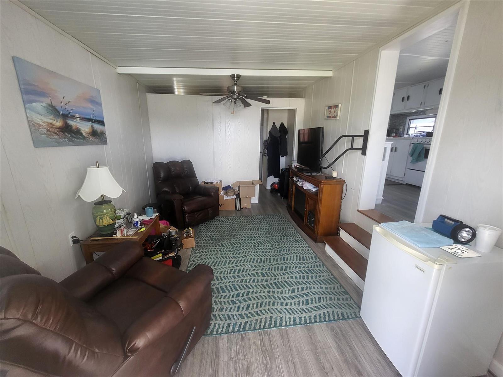 A living room with wood-paneled walls, two leather recliners, a patterned rug, and stairs — 6502 SE 54th Lane, Okeechobee FL 34974, OKEECHOBEE, FL
