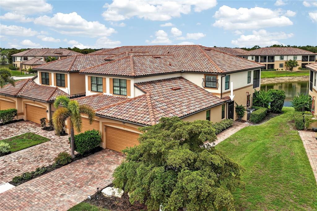 An aerial view shows a two-story townhouse with a tile roof and a brick driveway — 20151 RAGAZZA CIRCLE E UNIT 102, VENICE, FL