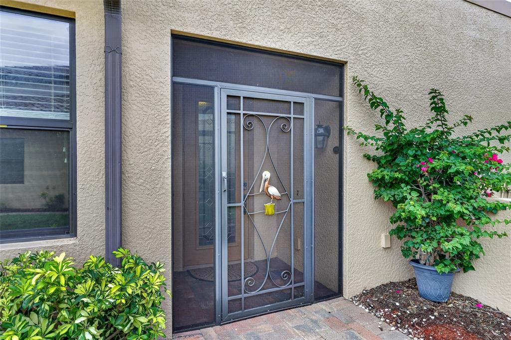 A metal screen door with a pelican decoration is installed at the home's entryway — 20151 RAGAZZA CIRCLE E UNIT 102, VENICE, FL