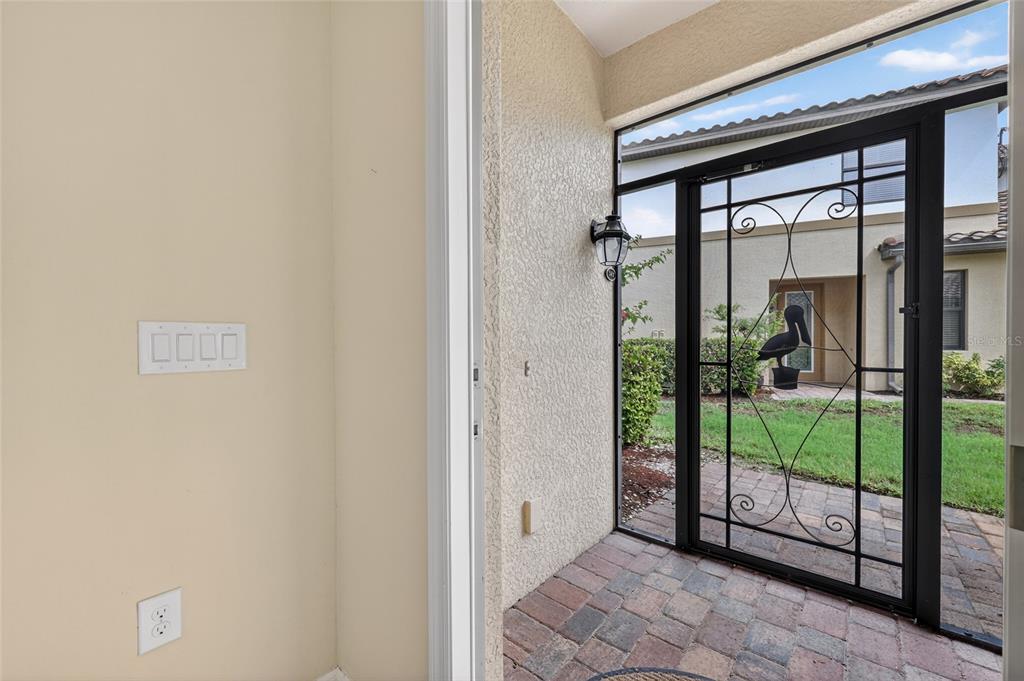 An indoor entryway with light walls leads to a screened-in patio with a decorative door — 20151 RAGAZZA CIRCLE E UNIT 102, VENICE, FL