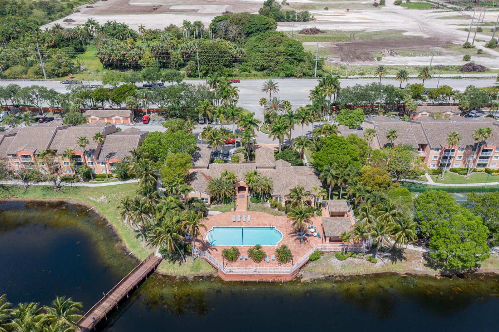 An aerial view shows a community clubhouse with a swimming pool overlooking a lake — 3844 Lyons Road # 4, Coconut Creek FL 33073, COCONUT CREEK, FL