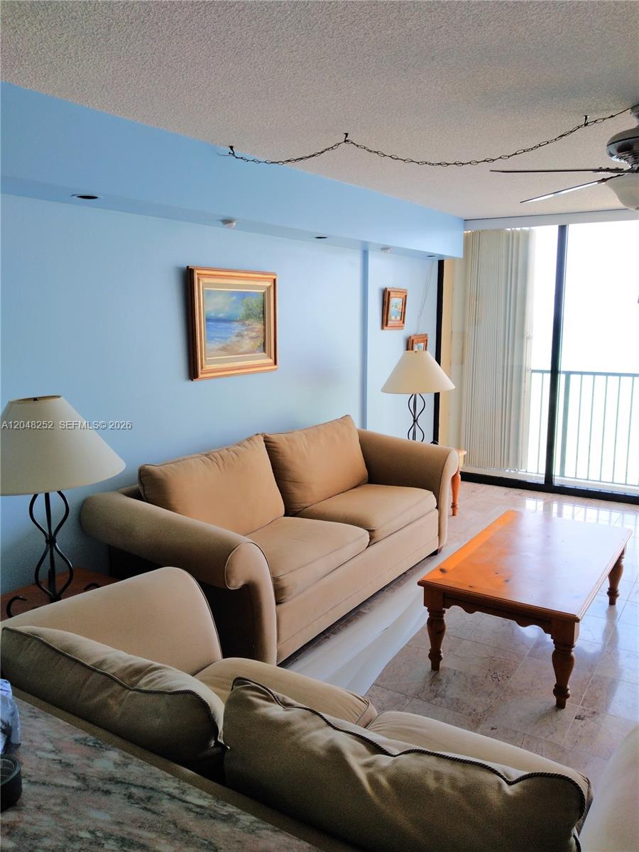 A living room features light blue walls, tan sofas, a wooden coffee table, and balcony access — 2101 S Ocean Dr # 2001, Hollywood FL 33019, HOLLYWOOD, FL