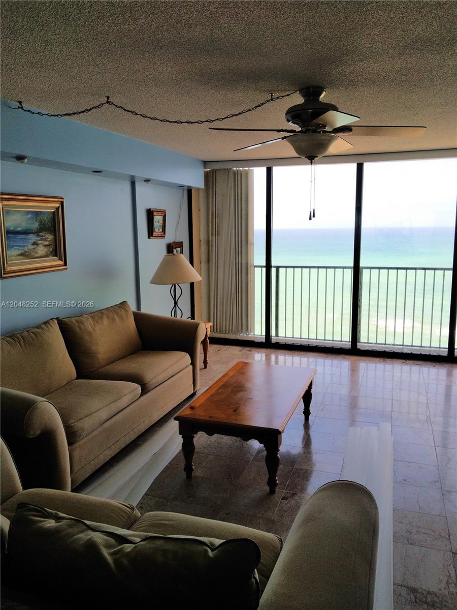 A living room features a beige sofa, wooden coffee table, tile floors, and ocean views — 2101 S Ocean Dr # 2001, Hollywood FL 33019, HOLLYWOOD, FL
