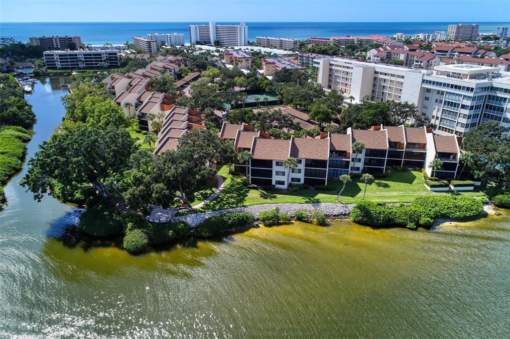 An aerial view shows waterfront condominium buildings surrounded by trees and a small canal — 1800 COVE II PLACE UNIT 213, SARASOTA, FL