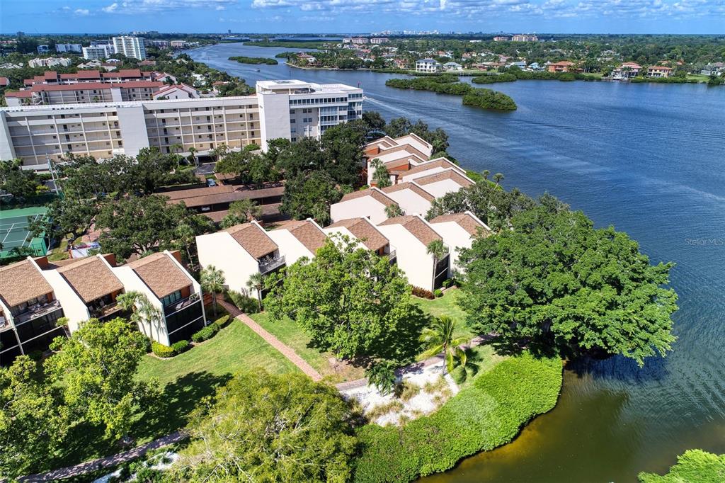 An aerial view shows waterfront townhomes with brown roofs situated next to a large apartment building — 1800 COVE II PLACE UNIT 213, SARASOTA, FL