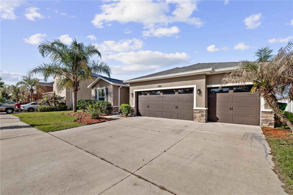 A single-story house with a three-car garage, palm trees, and a concrete driveway — 5453 SUNCATCHER DRIVE, WESLEY CHAPEL, FL