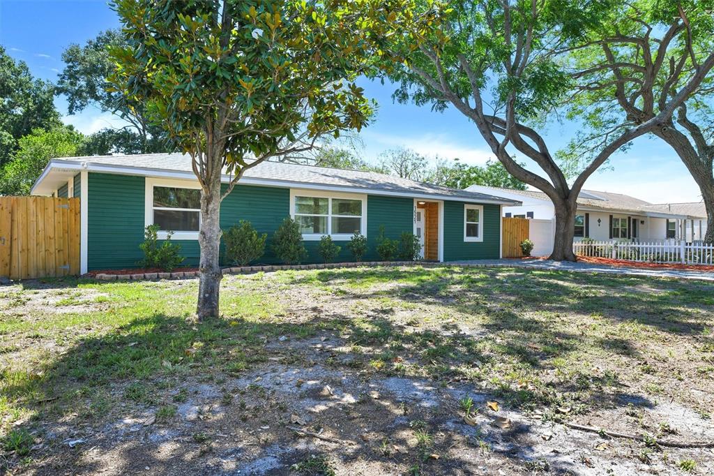 A single-story house with green horizontal siding and a front yard with large trees — 1521 S JEFFERSON AVENUE, CLEARWATER, FL