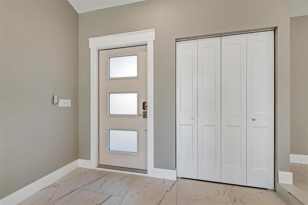 An entryway features a light-colored door with three glass panels and a white bifold closet — 1521 S JEFFERSON AVENUE, CLEARWATER, FL
