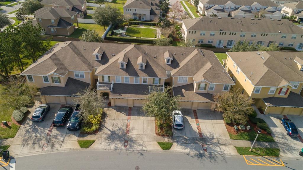 An aerial view of a multi-unit townhouse complex with attached garages and a paved street — 13942 DOVE WING COURT, ORLANDO, FL