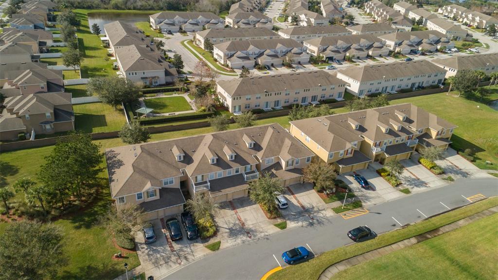 An aerial view shows multiple rows of suburban townhouses with driveways and surrounding green lawns — 13942 DOVE WING COURT, ORLANDO, FL