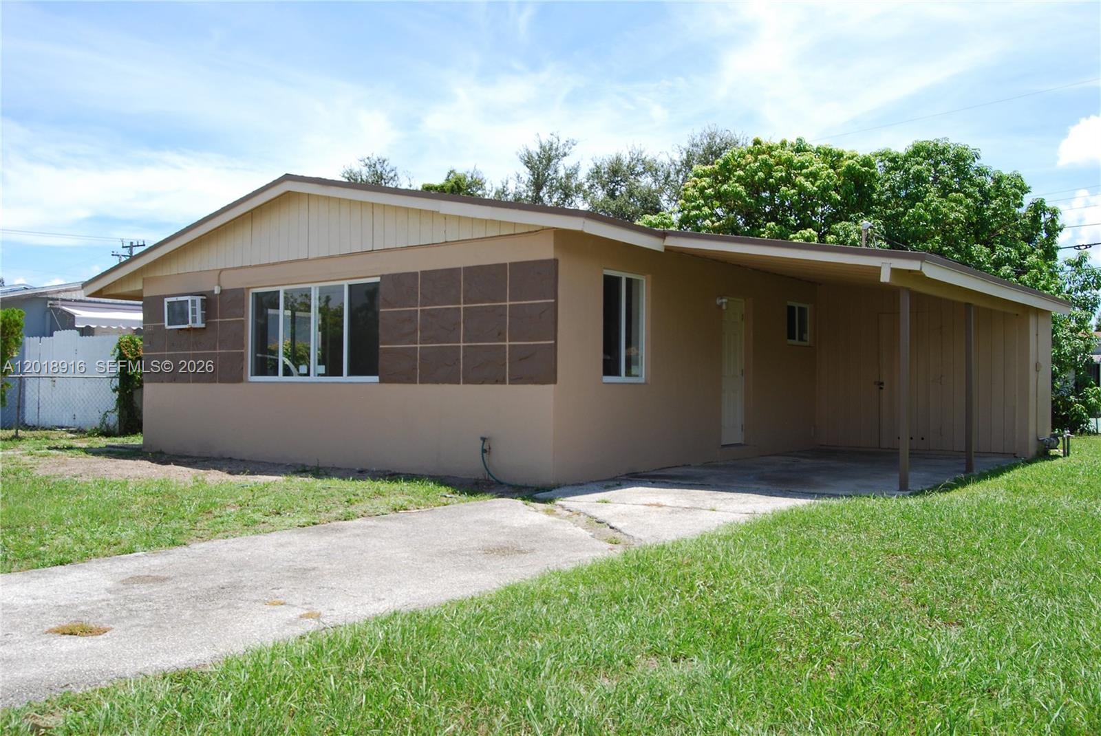 A single-story house with a tan exterior, brown accent panels, and an attached carport — 3020 NW 71st St, Miami FL 33147, MIAMI, FL
