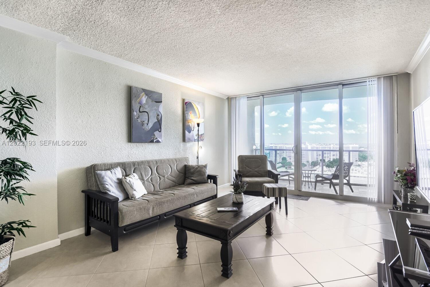 A living room features a sofa, coffee table, armchair, and a balcony with outdoor seating — 2501 S Ocean Dr # 1129, Hollywood FL 33019, HOLLYWOOD, FL