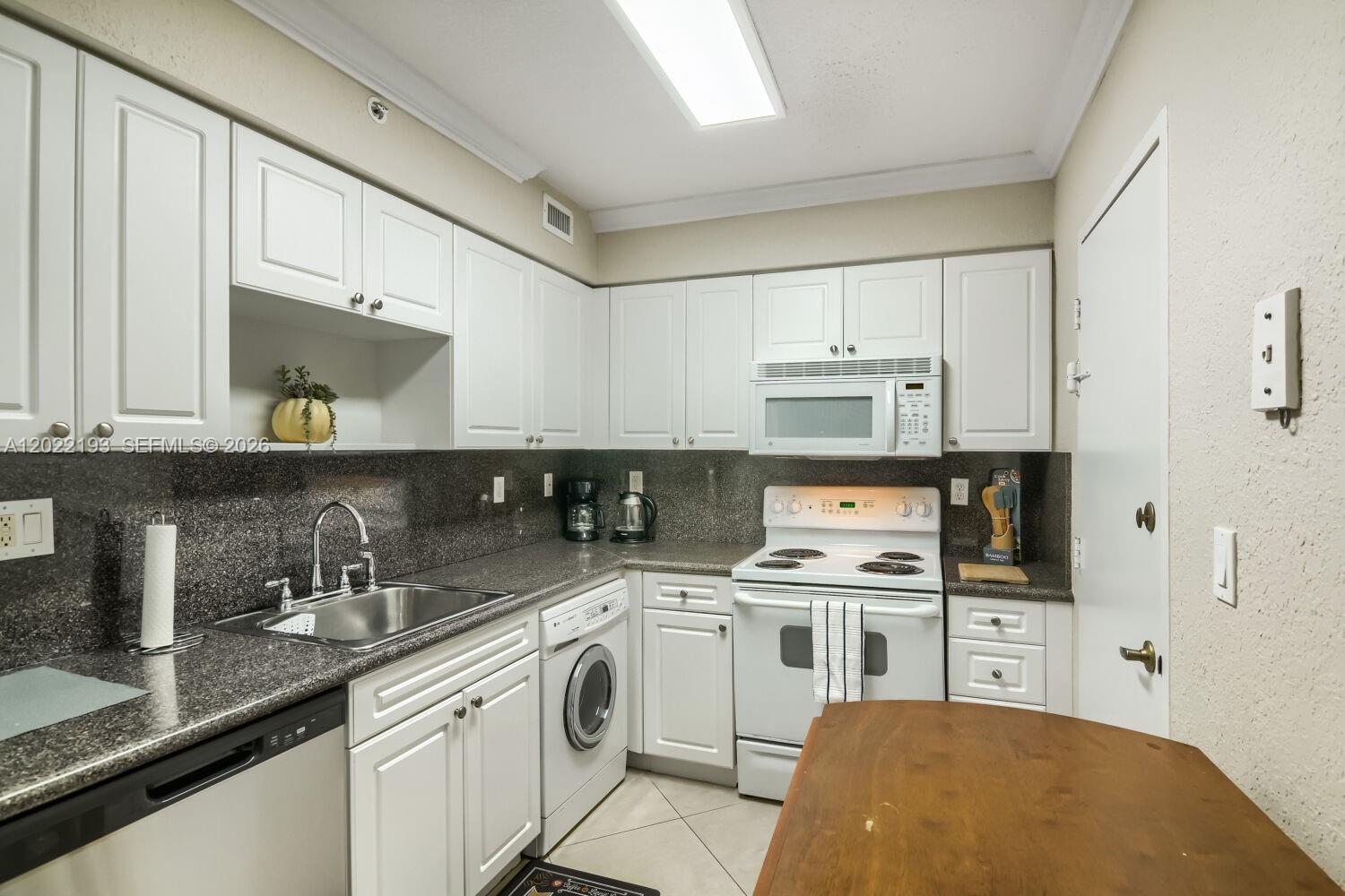 A kitchen features white cabinets, granite countertops, a stainless steel sink, and a built-in washer — 2501 S Ocean Dr # 1129, Hollywood FL 33019, HOLLYWOOD, FL