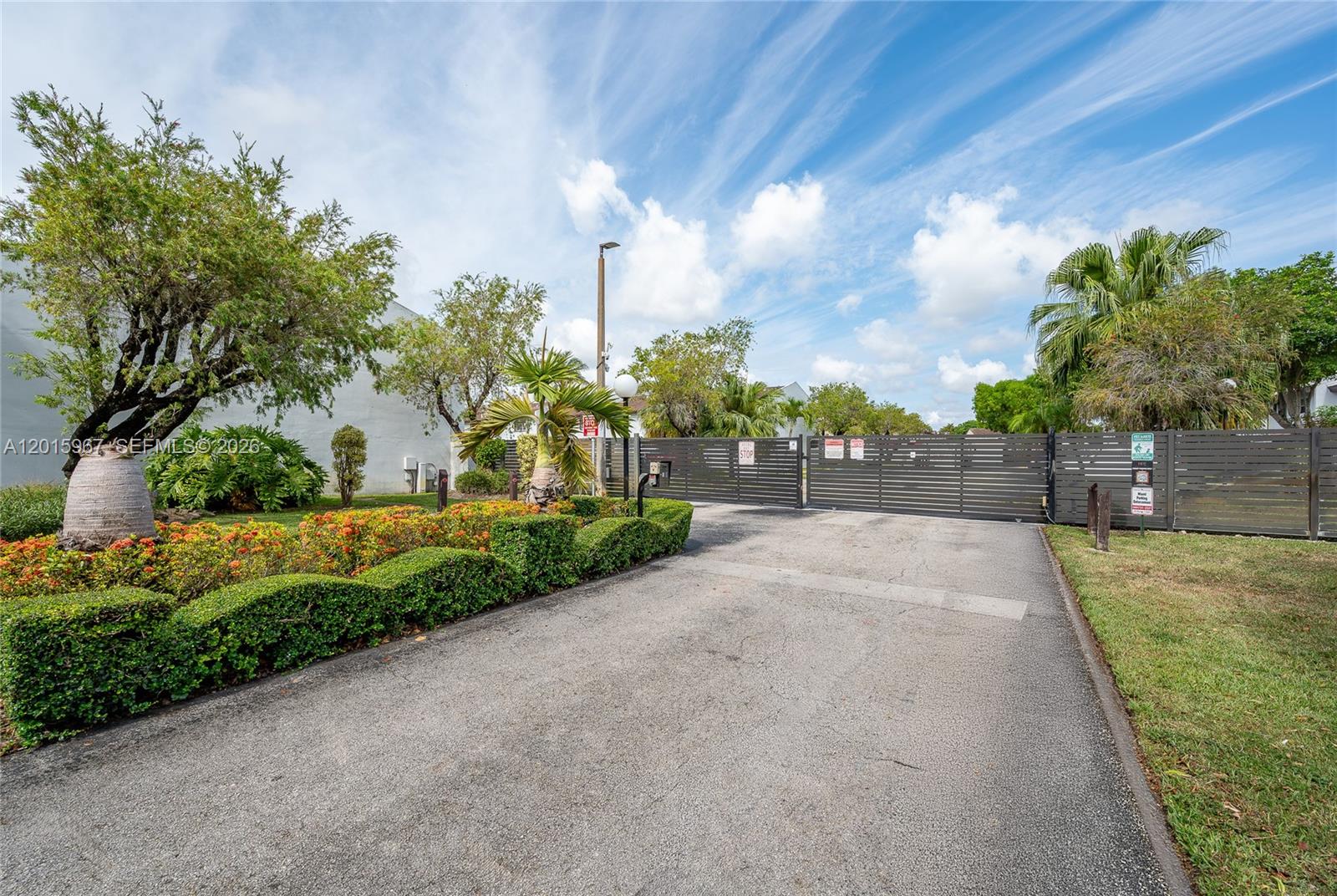 A paved driveway leads to a gated entrance surrounded by landscaping and trees — 8010 SW 152nd Ave # 211, Miami FL 33193, MIAMI, FL