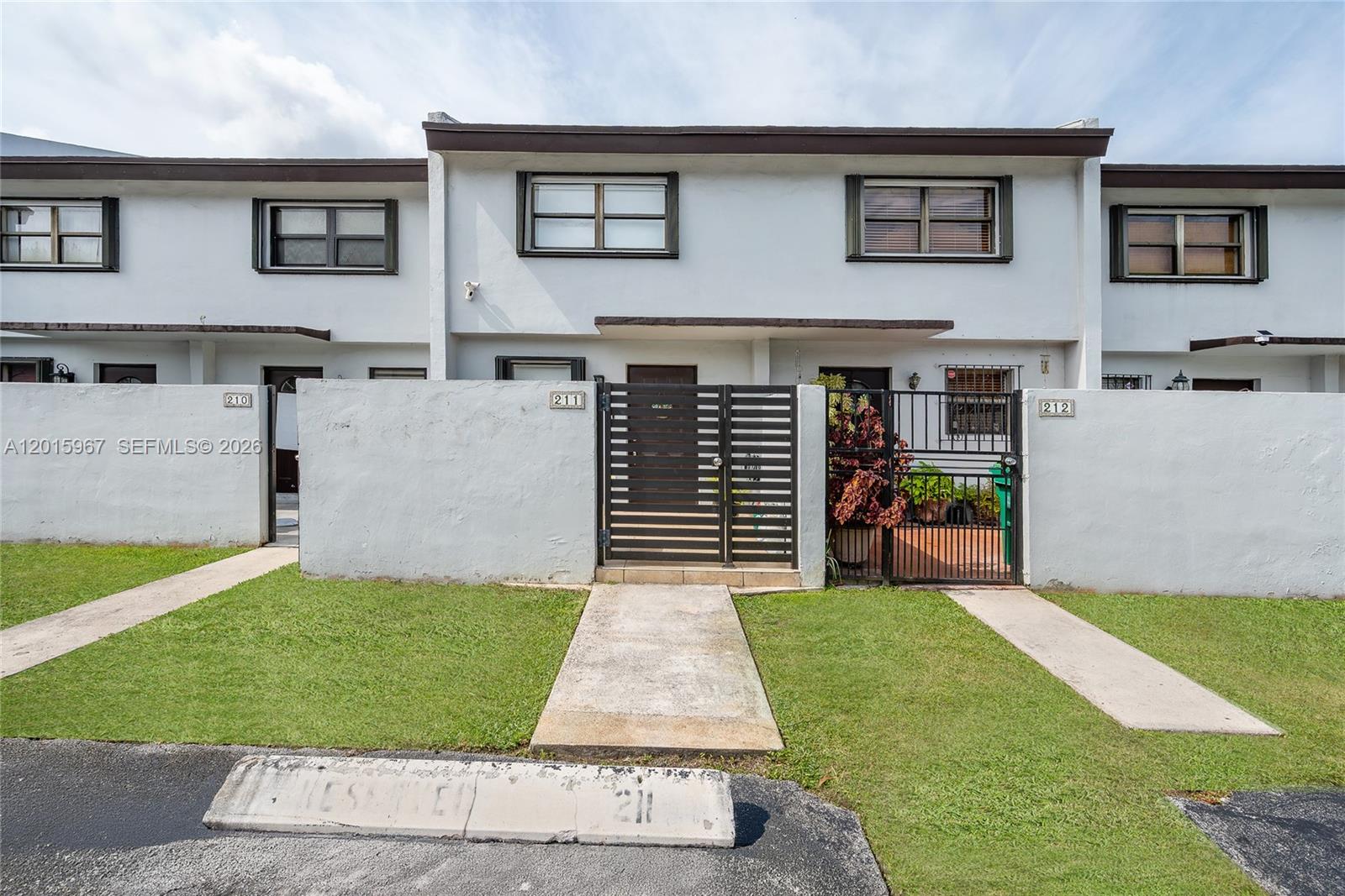 A row of townhouses features white stucco walls, private gated courtyards, and assigned parking spaces — 8010 SW 152nd Ave # 211, Miami FL 33193, MIAMI, FL