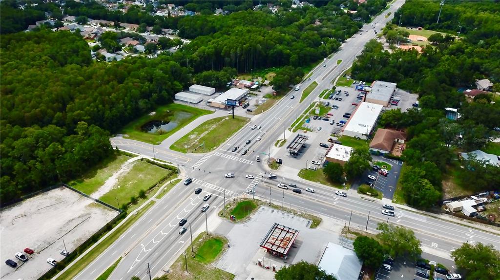 An aerial view shows a multi-lane intersection surrounded by commercial buildings, parking lots, and trees — 2318 SEVEN SPRINGS BOULEVARD, NEW PORT RICHEY, FL