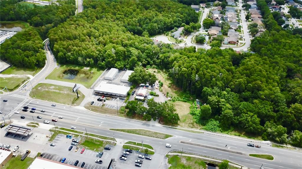 An aerial view shows a commercial property with buildings and parking lots near a highway — 2318 SEVEN SPRINGS BOULEVARD, NEW PORT RICHEY, FL