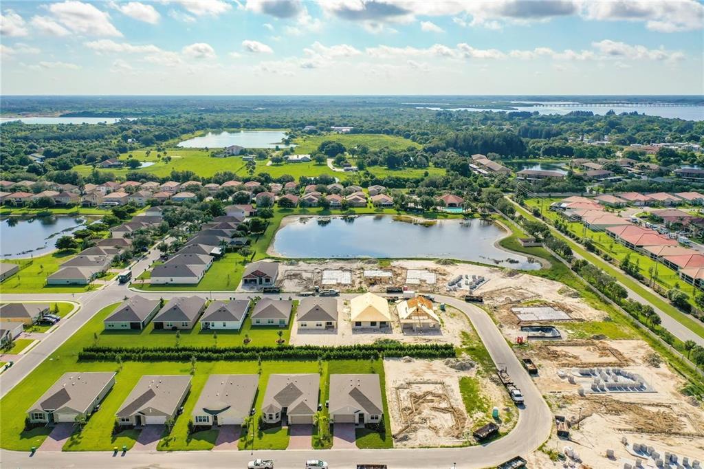 An aerial view shows a suburban neighborhood with completed homes, a pond, and active construction — 4203 MANATEE LANE, PUNTA GORDA, FL