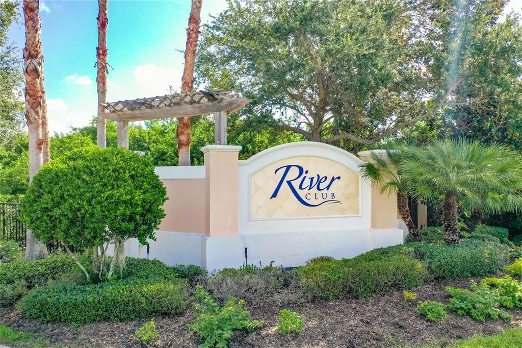 A beige monument sign for River Club stands in a landscaped area with palm trees — 4203 MANATEE LANE, PUNTA GORDA, FL