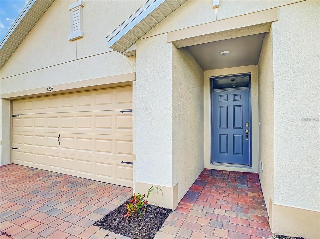 A beige garage door and a blue front door are set against a stucco exterior — 4203 MANATEE LANE, PUNTA GORDA, FL