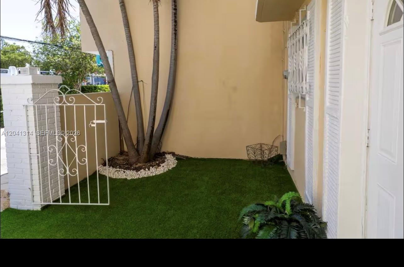 A small outdoor patio features artificial turf, a white metal gate, and a palm tree — 1949 NE 123rd St # 0, North Miami FL 33181, NORTH MIAMI, FL