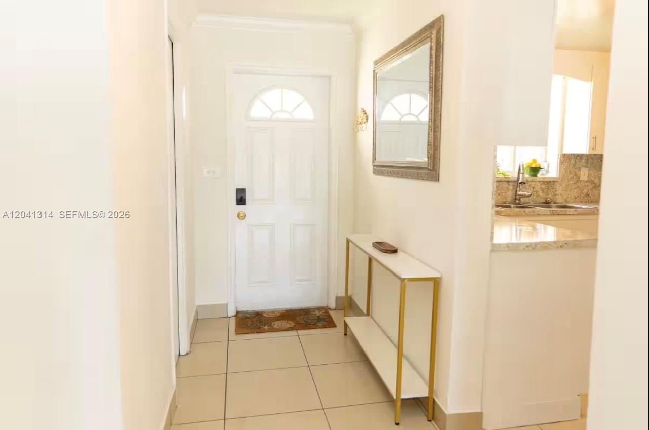 A white front door opens into a tiled entryway with a console table and mirror — 1949 NE 123rd St # 0, North Miami FL 33181, NORTH MIAMI, FL