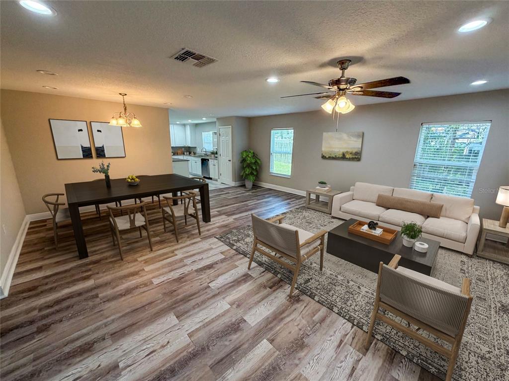An open-concept living and dining area features wood-look flooring, a ceiling fan, and neutral walls — 312 WADE AVENUE, DELAND, FL