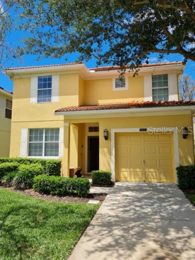 A two-story yellow house with a single-car garage and a paved driveway — 8923 CUBAN PALM ROAD, KISSIMMEE, FL