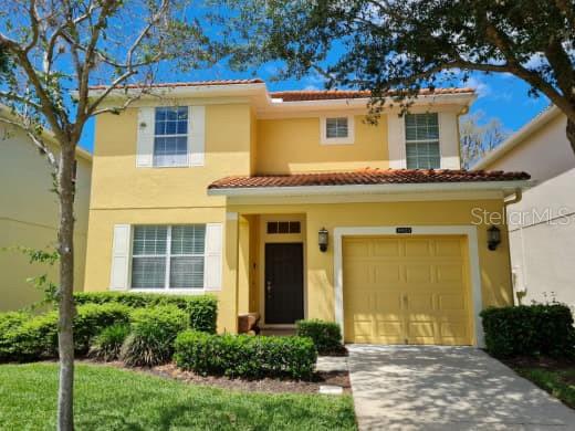 A two-story yellow house with a tile roof, a single-car garage, and a front lawn — 8923 CUBAN PALM ROAD, KISSIMMEE, FL