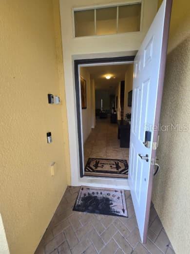 An open white front door reveals a tiled entryway leading into a home interior — 8923 CUBAN PALM ROAD, KISSIMMEE, FL