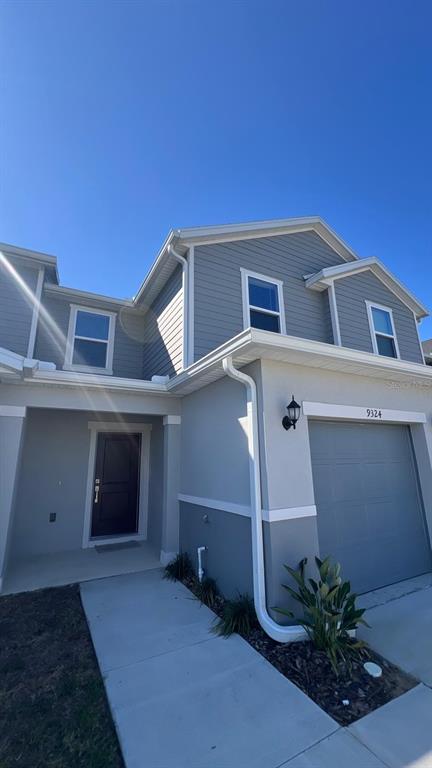 A two-story house exterior with gray siding, a dark front door, and a garage — 9324 WESTSIDE HILLS DRIVE, DAVENPORT, FL