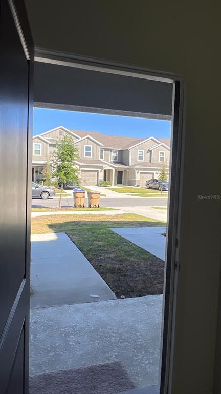 A view from an open doorway looking out at a suburban street and townhomes — 9324 WESTSIDE HILLS DRIVE, DAVENPORT, FL