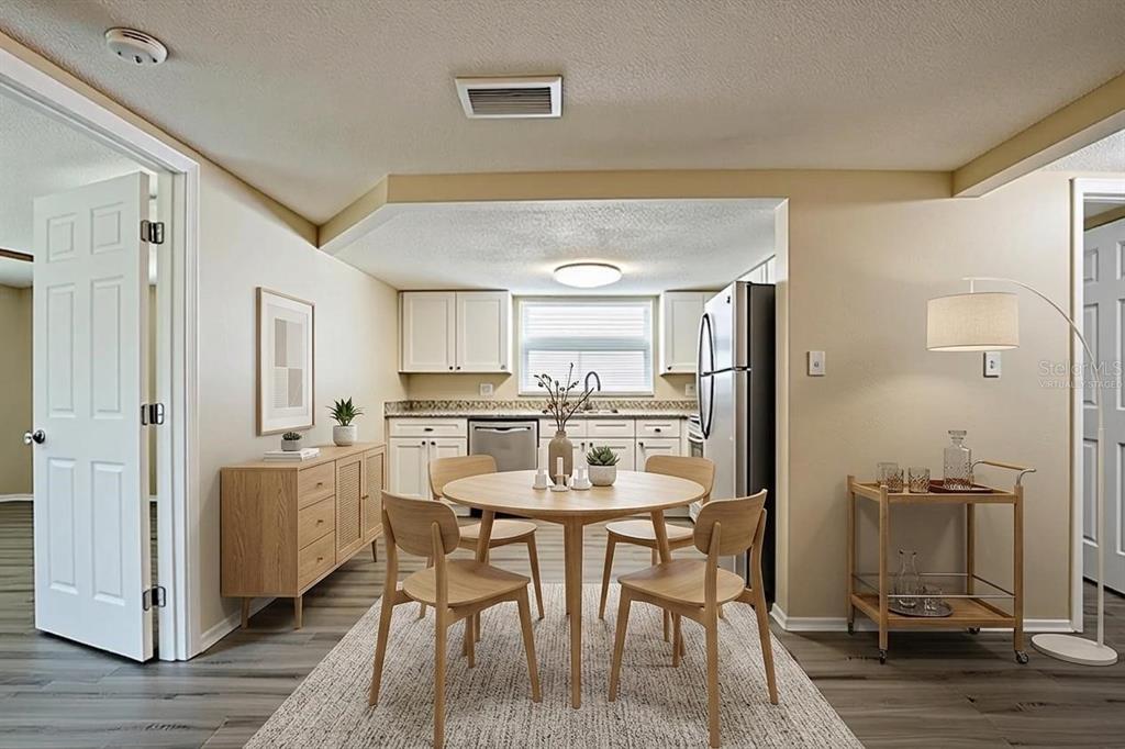 A dining area with a round wooden table and chairs sits in front of a kitchen — 9811 RAINBOW LANE, PORT RICHEY, FL