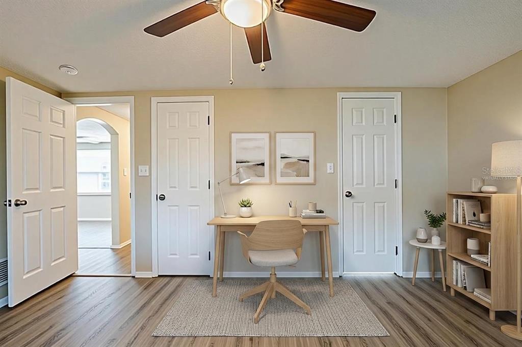A home office features a wooden desk, chair, area rug, and two closed white doors — 9811 RAINBOW LANE, PORT RICHEY, FL