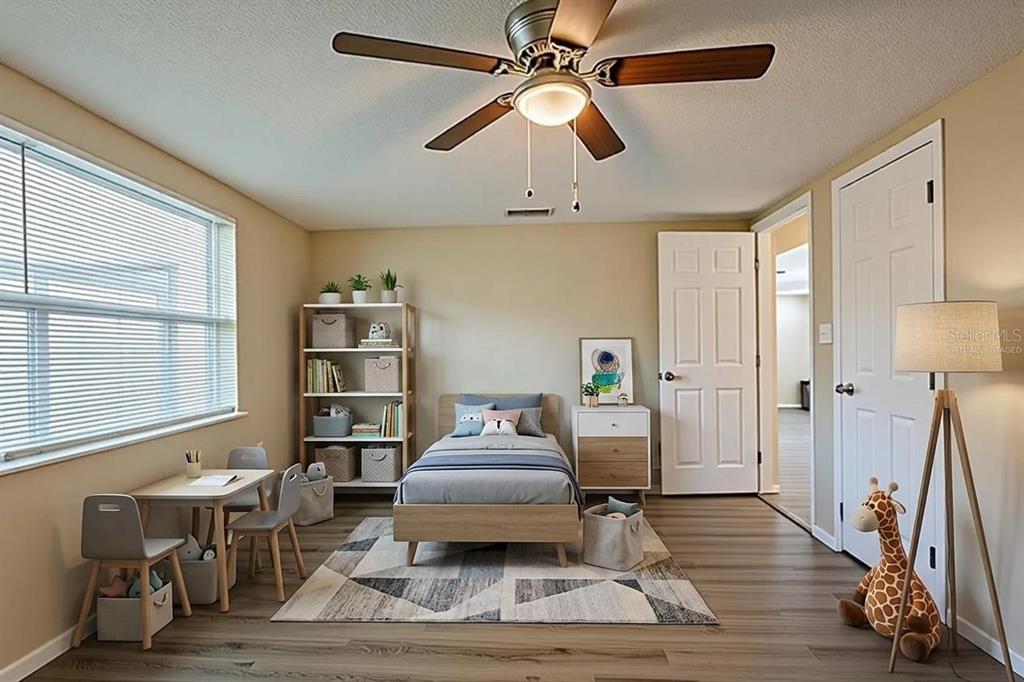 This bedroom features a single bed, a small table with chairs, and wood-look flooring — 9811 RAINBOW LANE, PORT RICHEY, FL