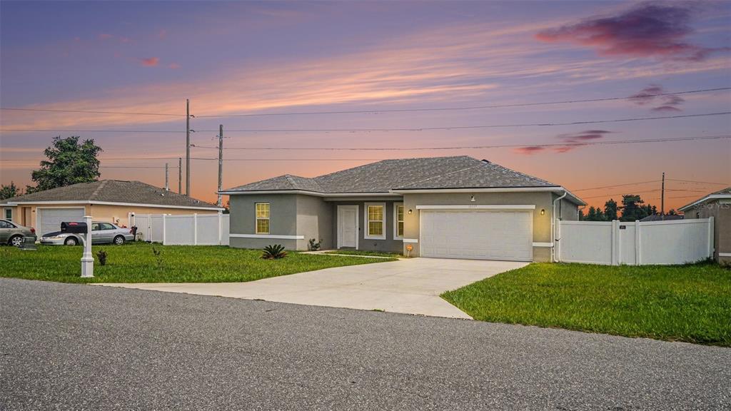 A single-story house with a gray stucco exterior, a two-car garage, and a white fence — 13537 SW 47TH CIRCLE, OCALA, FL