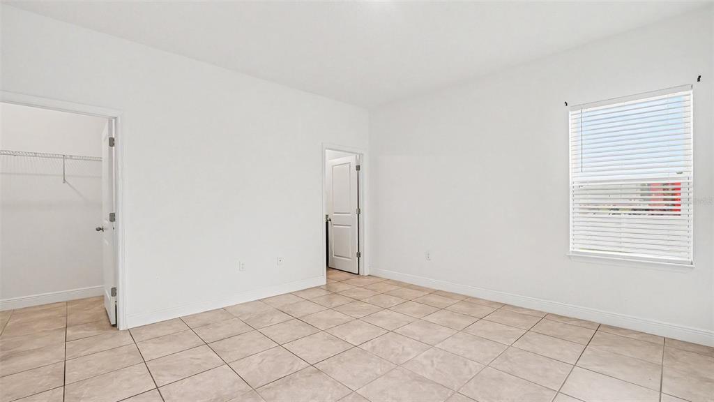 An empty bedroom with white walls, tile flooring, a closet, and a window with blinds — 13537 SW 47TH CIRCLE, OCALA, FL