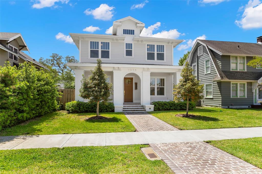 A two-story house with light gray siding, a white front porch, and a brick walkway — 1038 26TH AVENUE N, ST PETERSBURG, FL