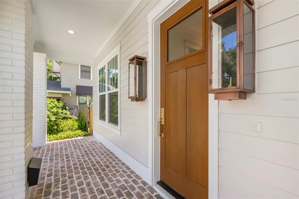 A front porch with a brick floor, a wooden door, and copper-colored wall lanterns — 1038 26TH AVENUE N, ST PETERSBURG, FL