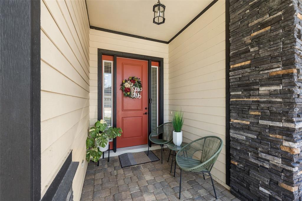 A front porch features a red door, stone siding, and two green chairs on pavers — 13688 NW 12TH PLACE, NEWBERRY, FL