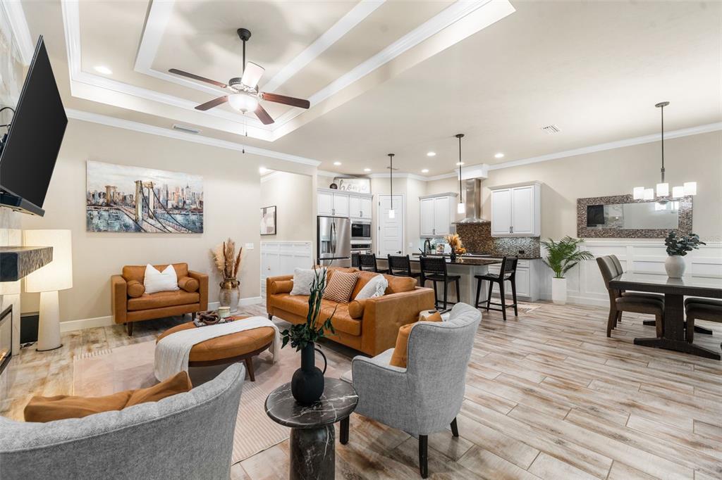 An open-concept living room and kitchen featuring wood-look tile flooring and a tray ceiling — 13688 NW 12TH PLACE, NEWBERRY, FL