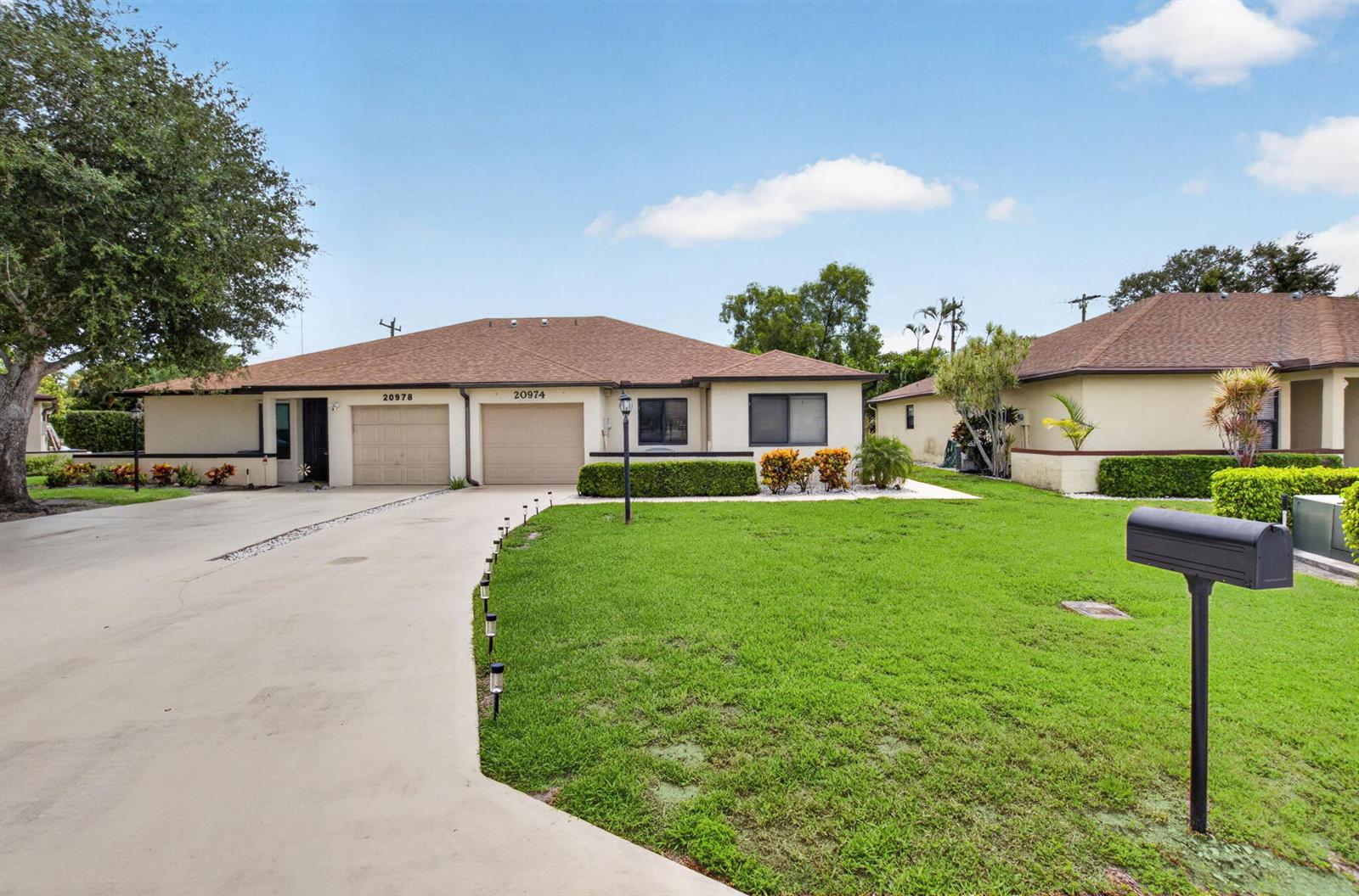 A single-story duplex with two garages, a concrete driveway, and a green lawn — 20974 Concord Green Drive E, Boca Raton FL 33433, BOCA RATON, FL