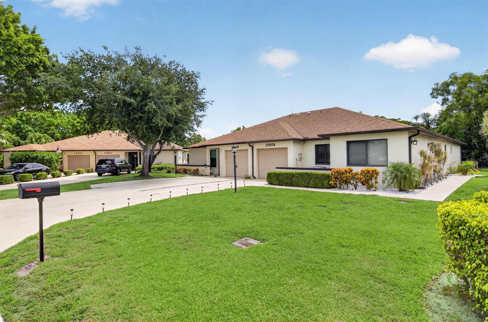 A single-story duplex with a tan exterior, two garage doors, and a large front lawn — 20974 Concord Green Drive E, Boca Raton FL 33433, BOCA RATON, FL