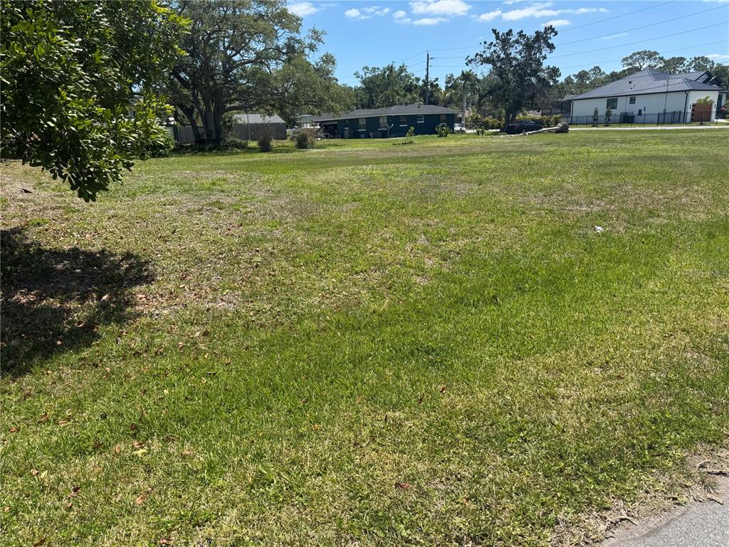 A large, flat, grassy vacant lot with trees and neighboring houses in the background — BONITO AVENUE, NOKOMIS, FL