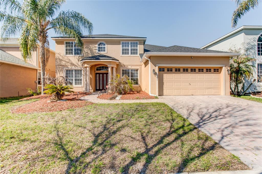 A two-story tan stucco house with a paved driveway and a two-car garage — 1551 AMARYLLIS CIRCLE, ORLANDO, FL