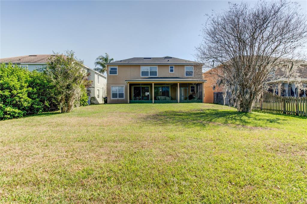 The rear exterior of a two-story house features a screened-in patio and a grassy yard — 1551 AMARYLLIS CIRCLE, ORLANDO, FL