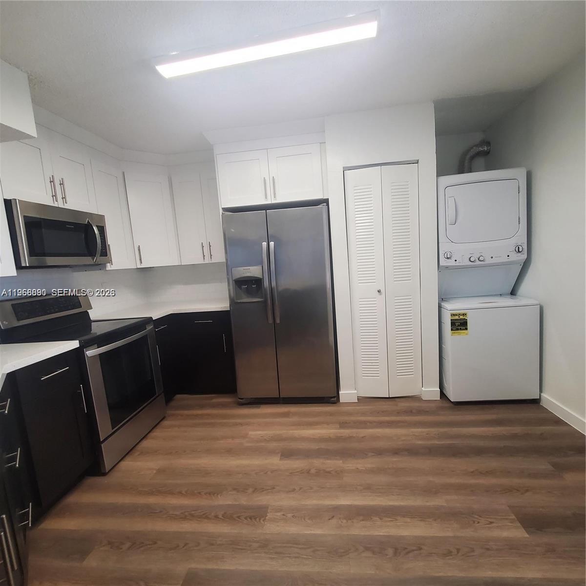 A kitchen features dark lower cabinets, white upper cabinets, stainless steel appliances, and a laundry unit — 929 Hamilton Dr # 929F, Homestead FL 33034, HOMESTEAD, FL